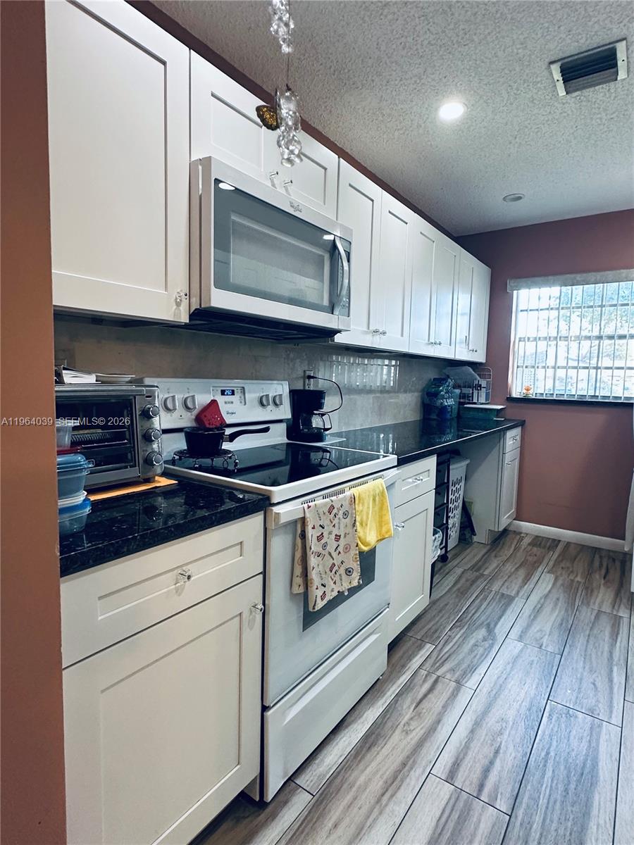 5260 Nesting Way, Unit B Delray Beach, FL 33484 - Photo 6 of 9 a kitchen with stainless steel appliances granite countertop a sink a stove and cabinets
