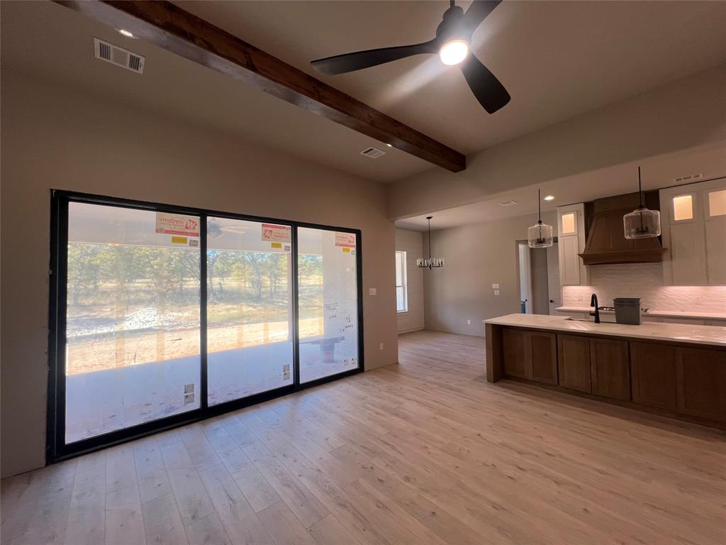 1053 Llano Way Poolville, TX 76487 - Photo 12 of 26 a large kitchen with stainless steel appliances granite countertop a stove a sink a large window and wooden floor