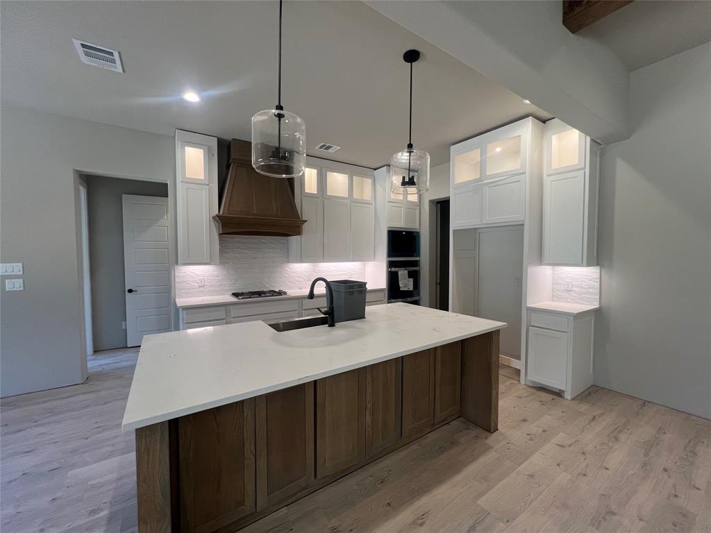1053 Llano Way Poolville, TX 76487 - Photo 13 of 26 a kitchen with a sink a stove and a wooden floor