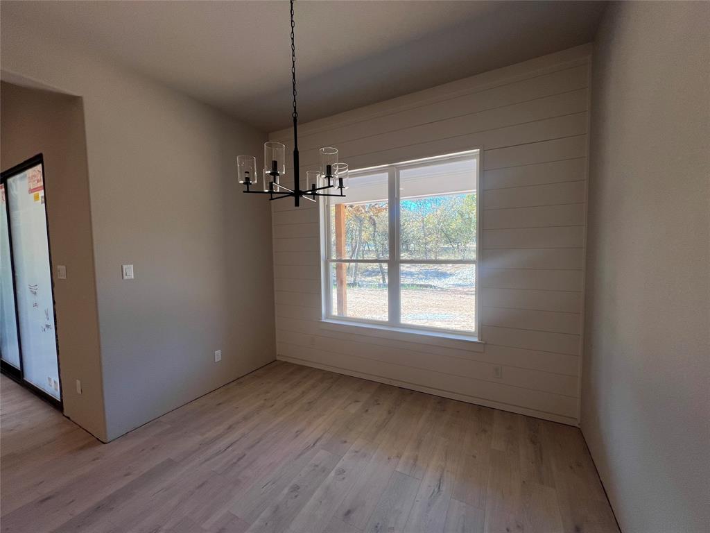 1053 Llano Way Poolville, TX 76487 - Photo 14 of 26 a view of an empty room with wooden floor fridge and a window