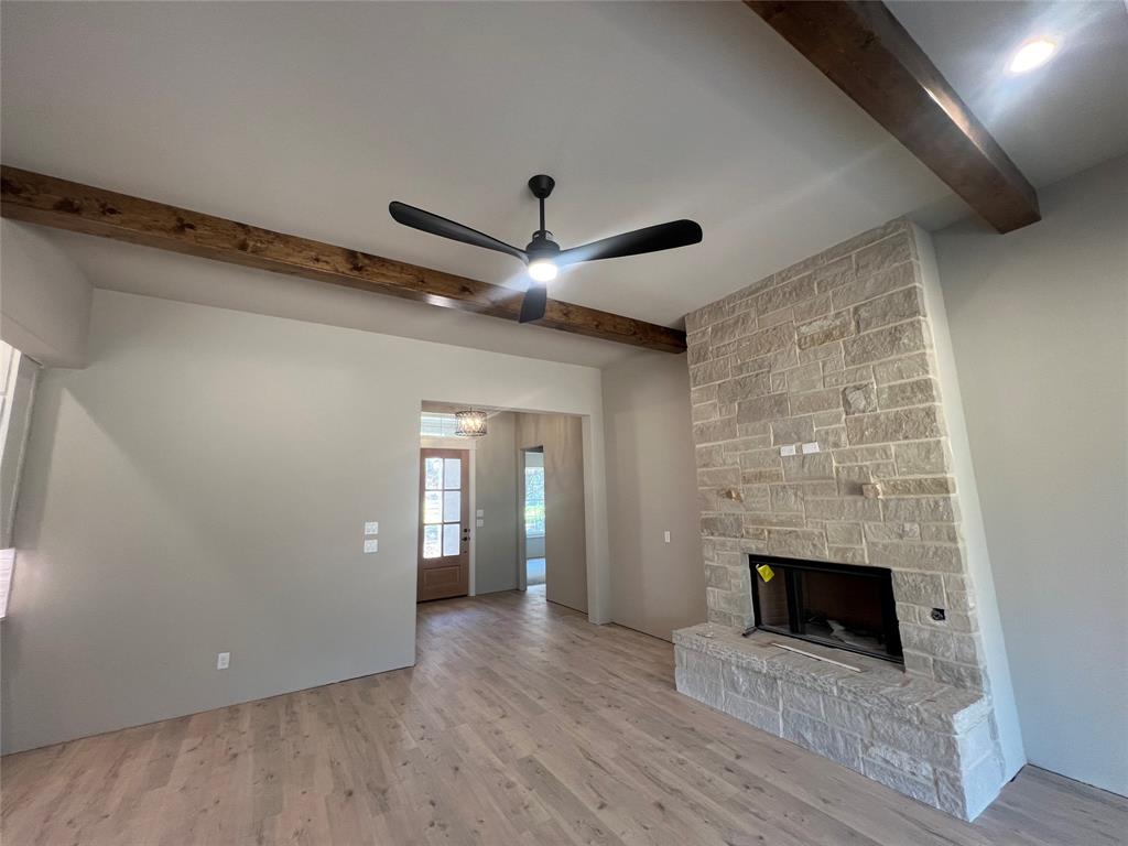 1053 Llano Way Poolville, TX 76487 - Photo 10 of 26 an empty room with wooden floor a fireplace and windows