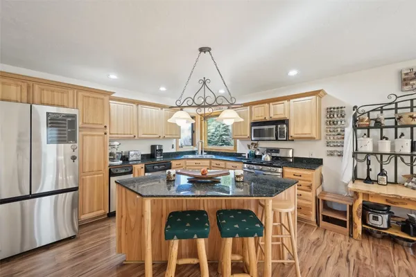 a kitchen with stainless steel appliances granite countertop a stove refrigerator and wooden floor