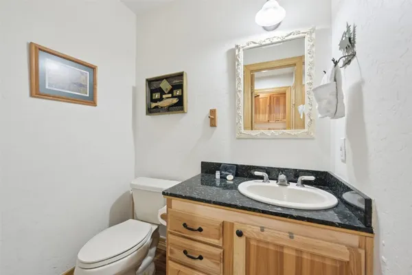 a bathroom with a toilet sink vanity granite and mirror