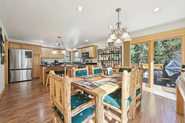 a open kitchen with stainless steel appliances granite countertop a stove refrigerator and a dining table with wooden floor