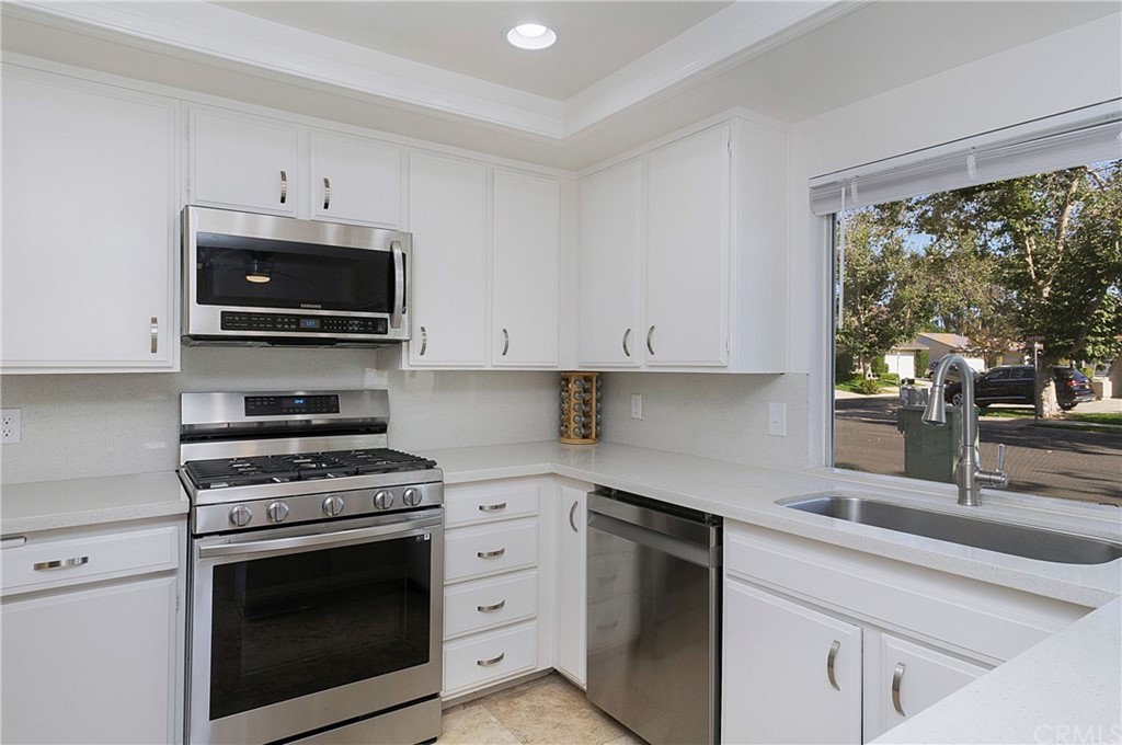 17241 Candleberry Irvine, CA 92612 - Photo 4 of 24 a kitchen with granite countertop a stove a microwave a sink and cabinets