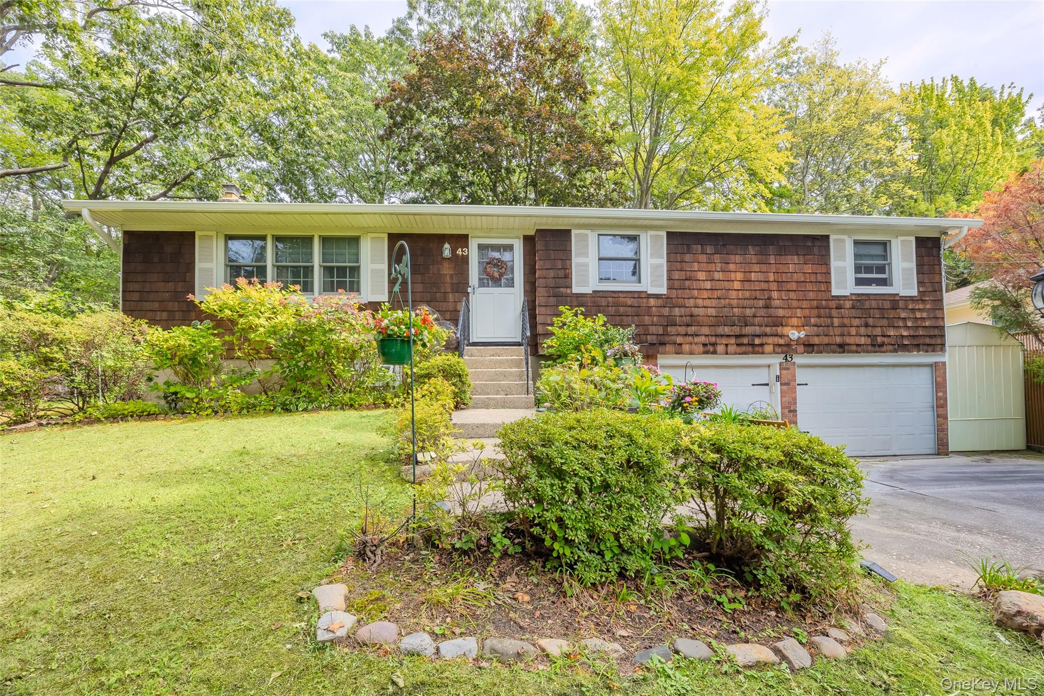 43 Flowerfield Road Sound Beach, NY 11789 - Photo 1 of 1 View of front of property with concrete driveway, a garage, a front yard, and entry steps