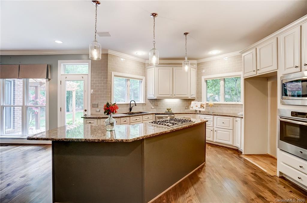 18408 Dembridge Drive, Unit 21 Davidson, NC 28036 - Photo 11 of 34 a kitchen with kitchen island granite countertop a stove a sink a center island and wooden floor