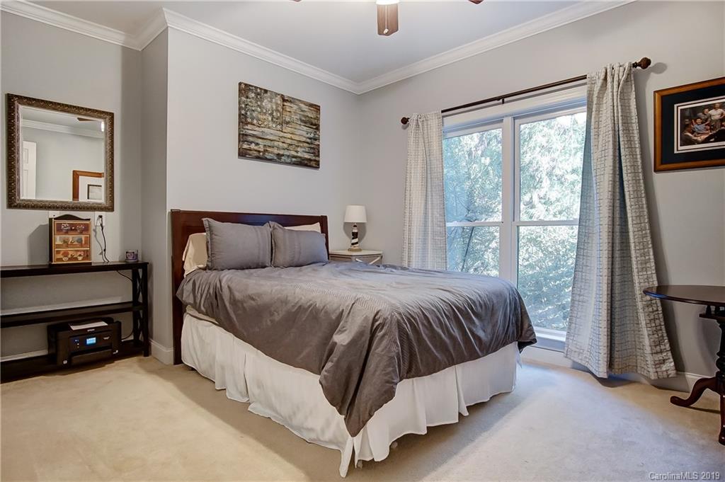 18408 Dembridge Drive, Unit 21 Davidson, NC 28036 - Photo 20 of 34 a spacious bedroom with a bed and a flat tv screen on the dresser