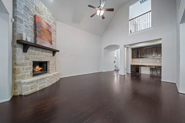 a view of an empty room with wooden floor fireplace and a window