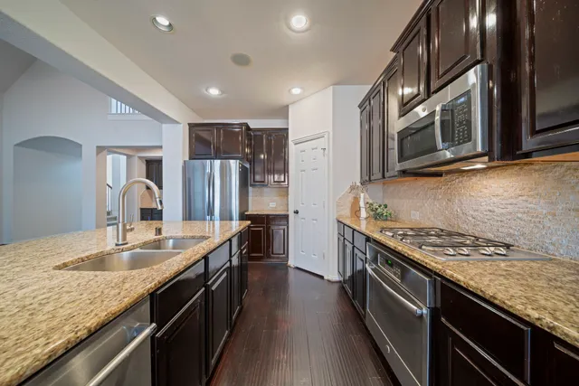 a kitchen with stainless steel appliances granite countertop a sink stove and refrigerator