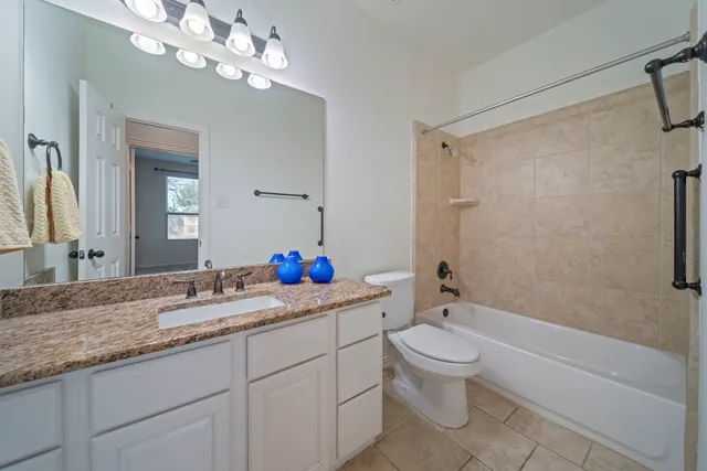 a bathroom with a granite countertop sink a toilet and a mirror