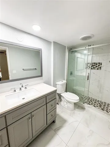 a bathroom with a granite countertop sink toilet and shower
