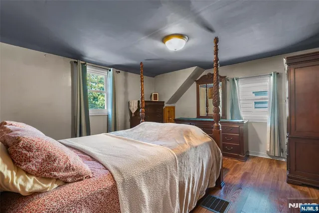a bedroom with a bed dresser and a wooden floor
