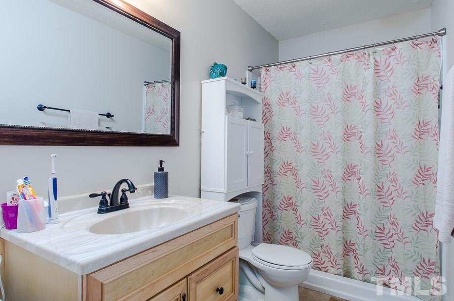 5521 Edgebury Road Raleigh, NC 27613 - Photo 15 of 19 a bathroom with a sink a toilet and a mirror