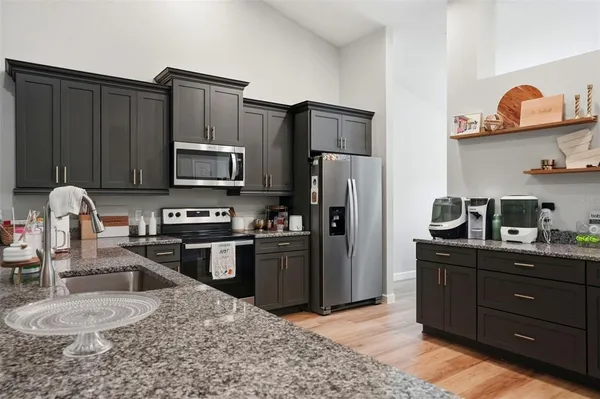 a kitchen with granite countertop white cabinets and stainless steel appliances