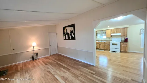 a view of a kitchen and an empty room with wooden floor
