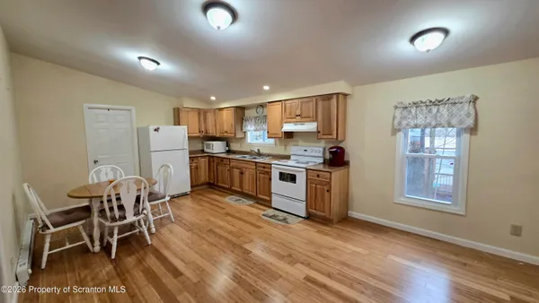 a kitchen with stainless steel appliances kitchen island granite countertop a refrigerator a stove a sink a dining table and chairs with wooden floor