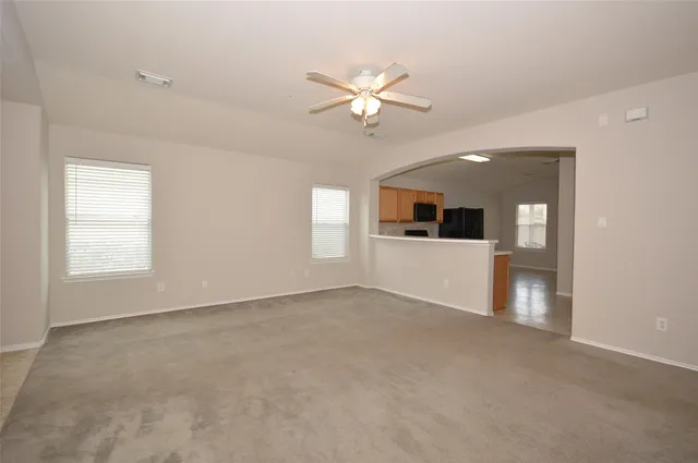 en empty room with windows and ceiling fan