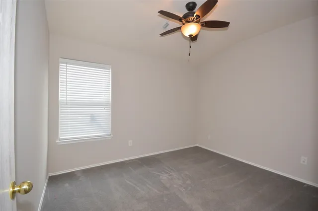 an empty room with a window and a fan