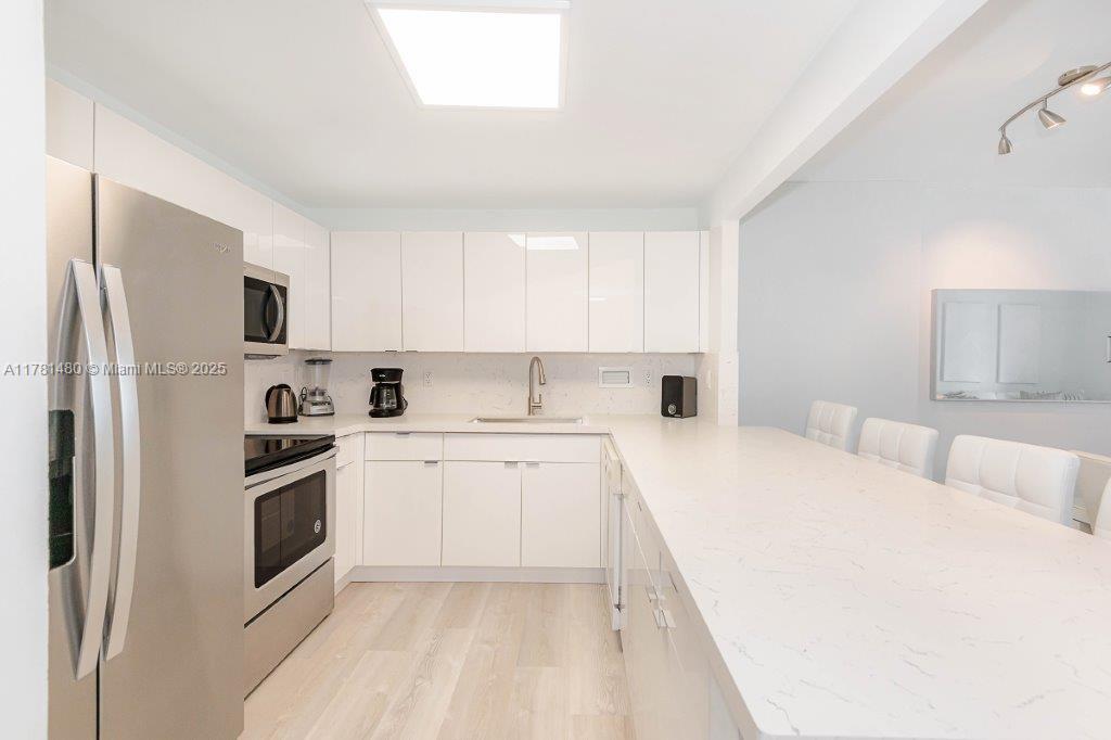 2301 Collins Avenue, Unit 401 Miami Beach, FL 33139 - Photo 22 of 38 a kitchen with stainless steel appliances a refrigerator sink and microwave