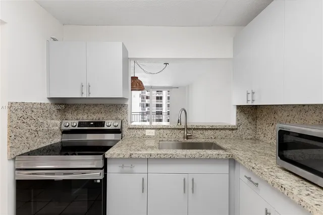 a kitchen with granite countertop a stove sink and microwave