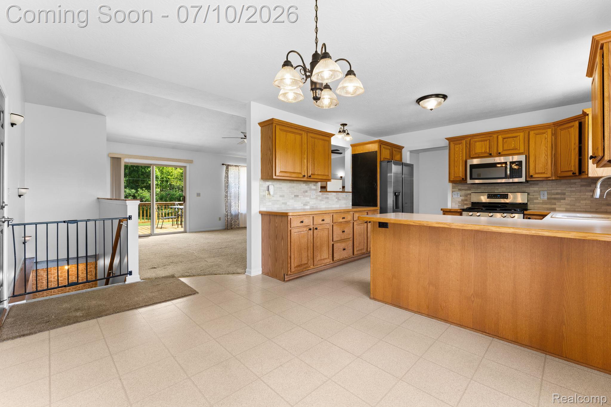 3144 North Nicholson Road Fowlerville, MI 48836 - Photo 39 of 70 Kitchen featuring light wood cabinetry, a central island, stainless steel appliances, and a tiled backsplash