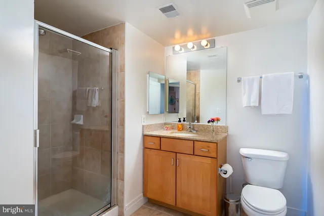 a bathroom with a toilet sink vanity granite and shower