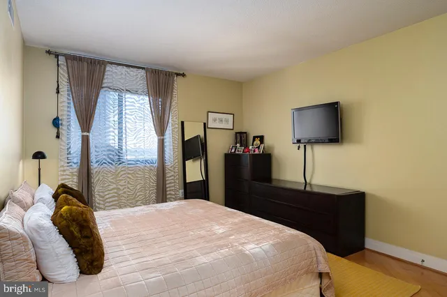 a bedroom with a bed and a flat tv screen next to a window