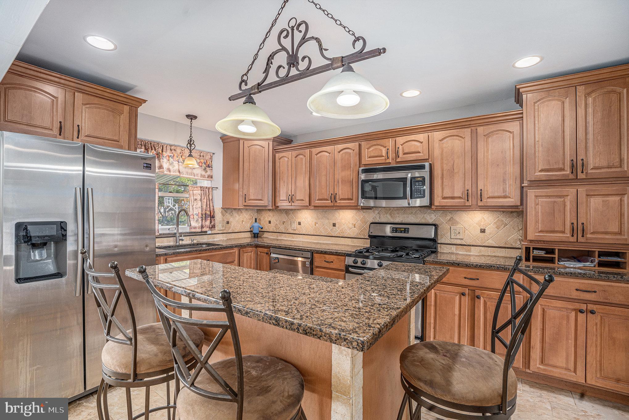 621 Kismet Road Philadelphia, PA 19115 - Photo 11 of 38 a kitchen with stainless steel appliances granite countertop a stove top oven a refrigerator a sink and a dining table with chairs