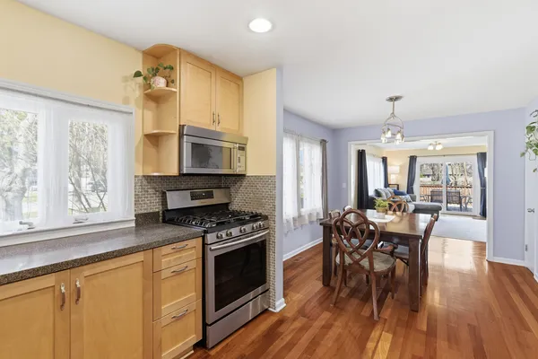 a kitchen with stainless steel appliances a dining table chairs stove and wooden floor