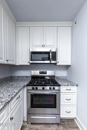 a kitchen with granite countertop white cabinets and stainless steel appliances