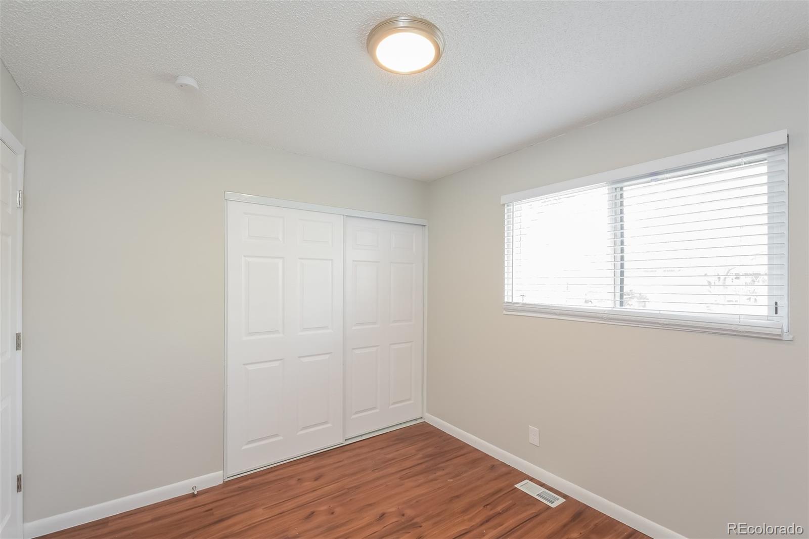 5522 Carson Street Denver, CO 80239 - Photo 12 of 17 an empty room with wooden floor and windows