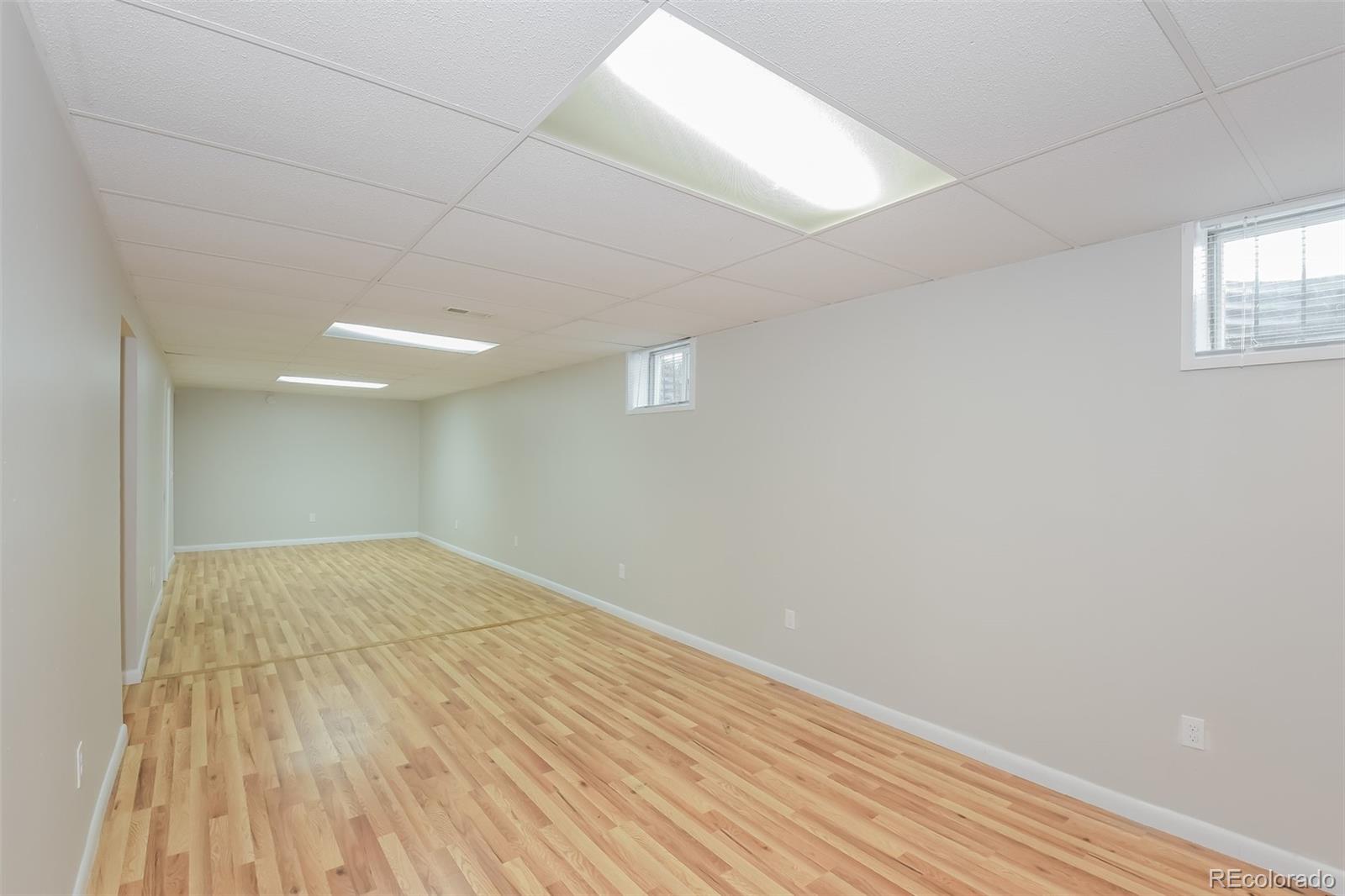 5522 Carson Street Denver, CO 80239 - Photo 13 of 17 an empty room with wooden floor and windows