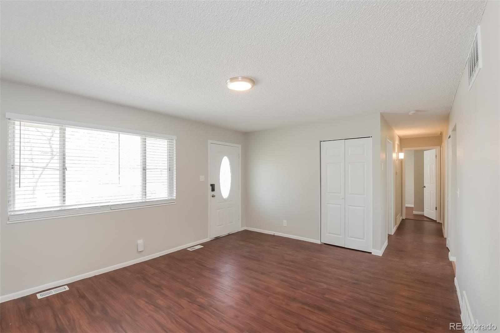 5522 Carson Street Denver, CO 80239 - Photo 2 of 17 an empty room with wooden floor and windows