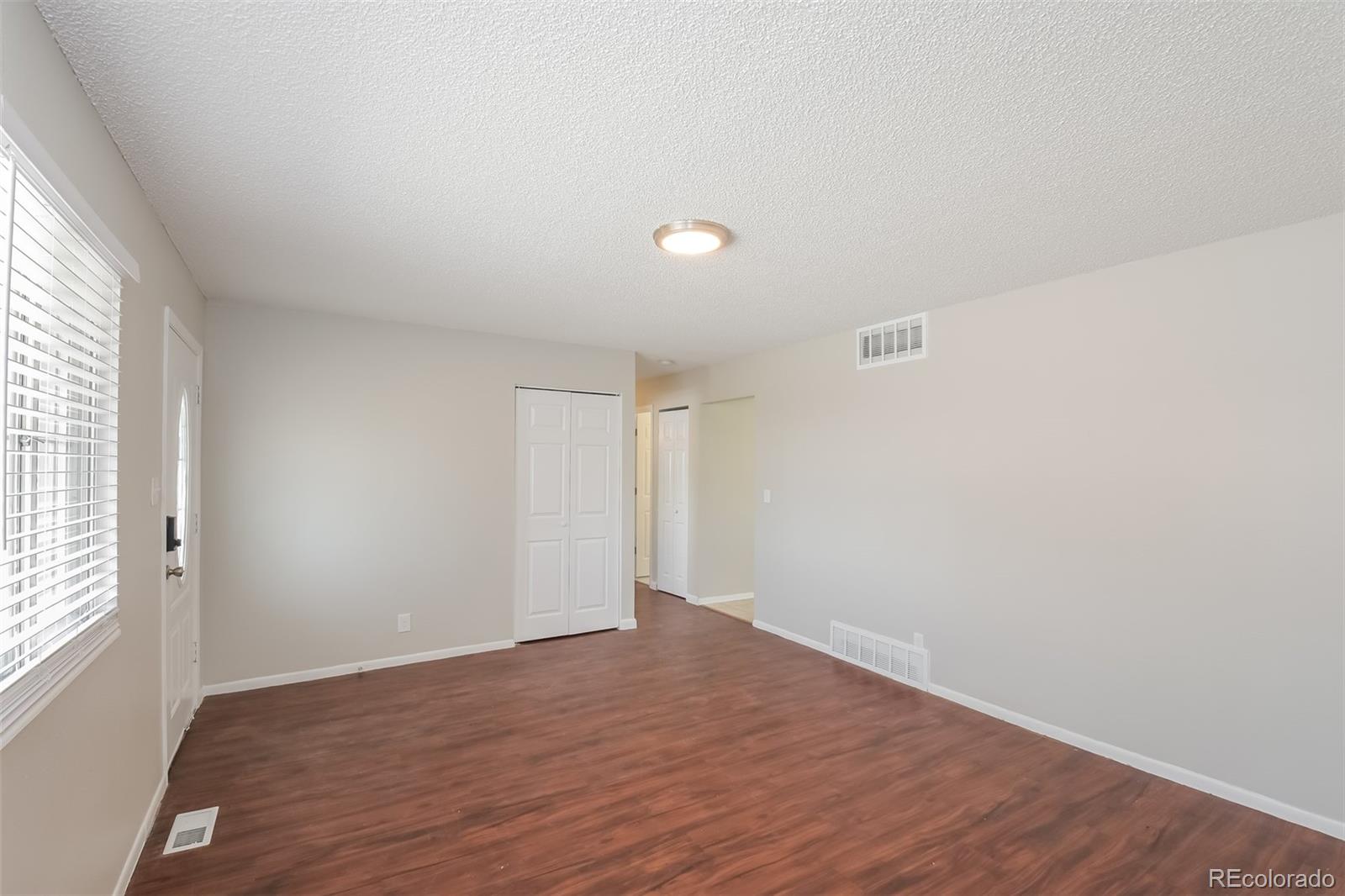 5522 Carson Street Denver, CO 80239 - Photo 3 of 17 an empty room with wooden floor and windows