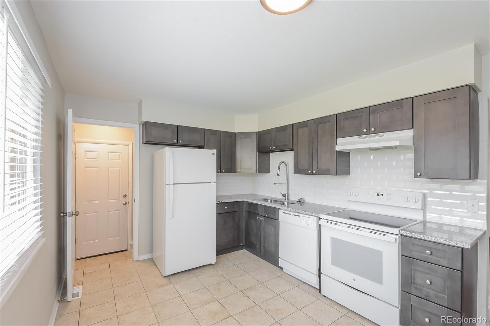 5522 Carson Street Denver, CO 80239 - Photo 6 of 17 a kitchen with a sink a refrigerator and cabinets