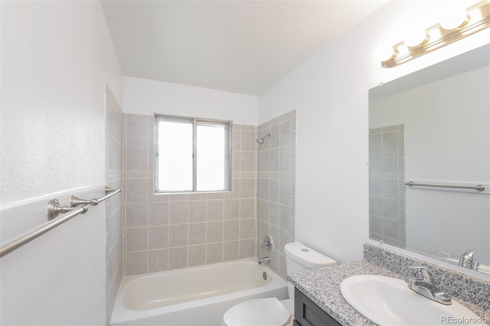 5522 Carson Street Denver, CO 80239 - Photo 8 of 17 a bathroom with a granite countertop sink toilet and shower