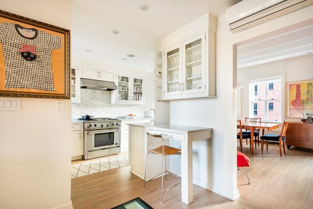 69 Washington Place, Unit 3/4/5 Manhattan, NY 10011 - Photo 7 of 26 a kitchen with stainless steel appliances granite countertop a stove top oven a sink a dining table and chairs with wooden floor
