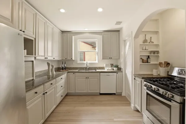 a kitchen with granite countertop a sink stove and cabinets