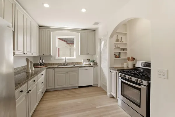 a kitchen with granite countertop a sink stove and cabinets