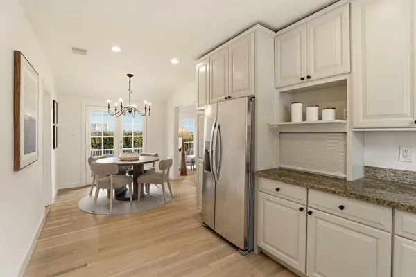 a kitchen with stainless steel appliances granite countertop a refrigerator a stove a sink a dining table and chairs with wooden floor