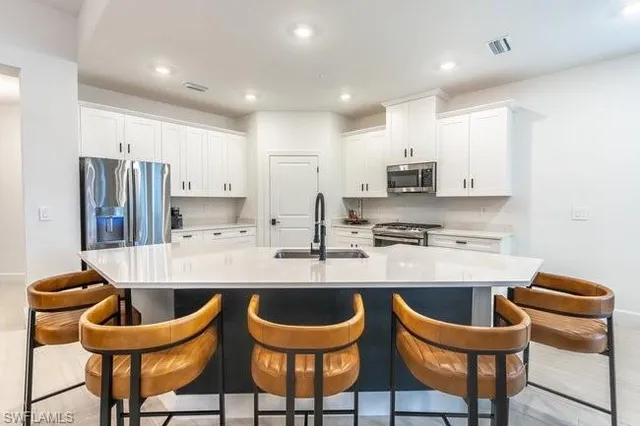 a kitchen with stainless steel appliances granite countertop a sink a stove and a wooden cabinets