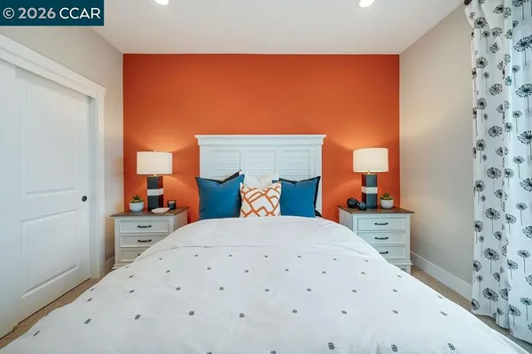 a bedroom with a bed and a lamp on the wall