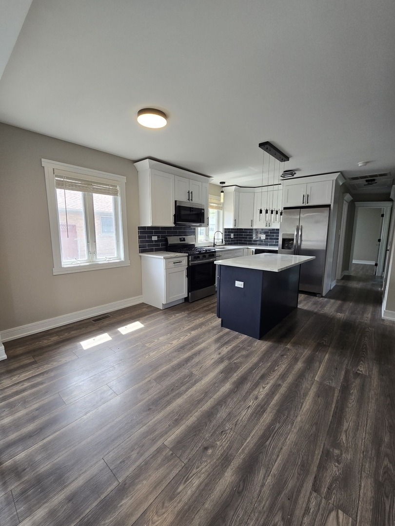 6024 Birmingham Street Chicago Ridge, IL 60415 - Photo 12 of 21 a large kitchen with kitchen island granite countertop a sink cabinets and wooden floor
