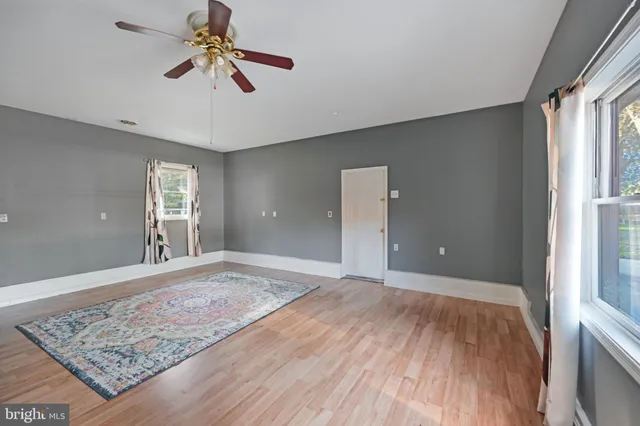 a view of a big room with wooden floor and windows