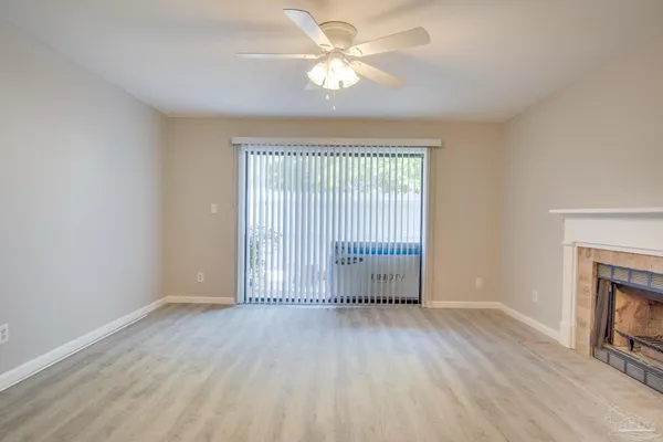 an empty room with wooden floor fan and windows