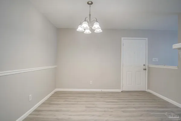 a view of an empty room with wooden floor and windows