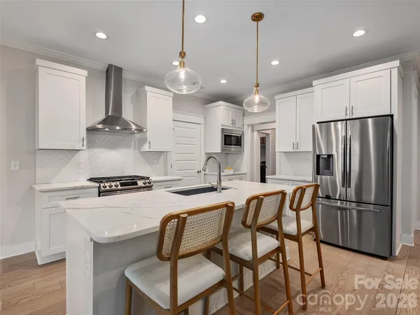 a kitchen with stainless steel appliances granite countertop a stove a refrigerator a kitchen island a sink and a refrigerator