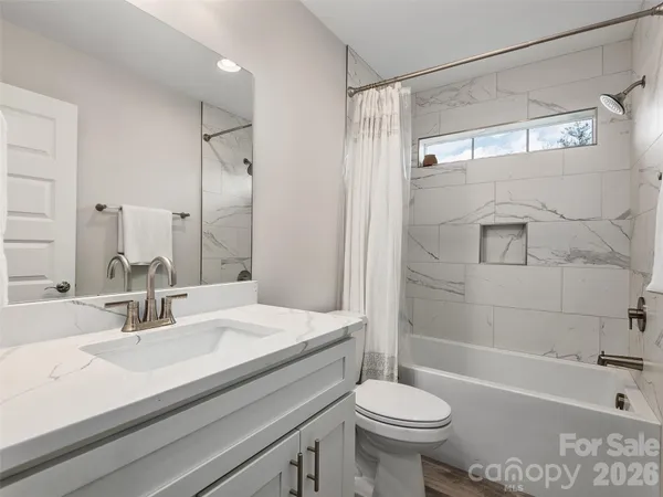 a bathroom with a sink toilet mirror and shower