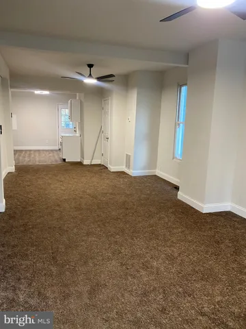 an empty room with staircase and ceiling fan